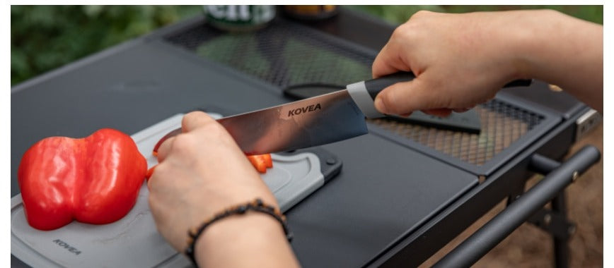 Hands using the Cooking Tool Set knife to slice a bell pepper on a camp table