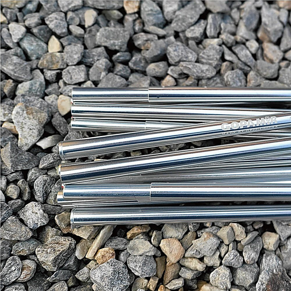 Polished aluminum Gopamir T720+ spare pole sections engraved with the brand name, laid across gray gravel