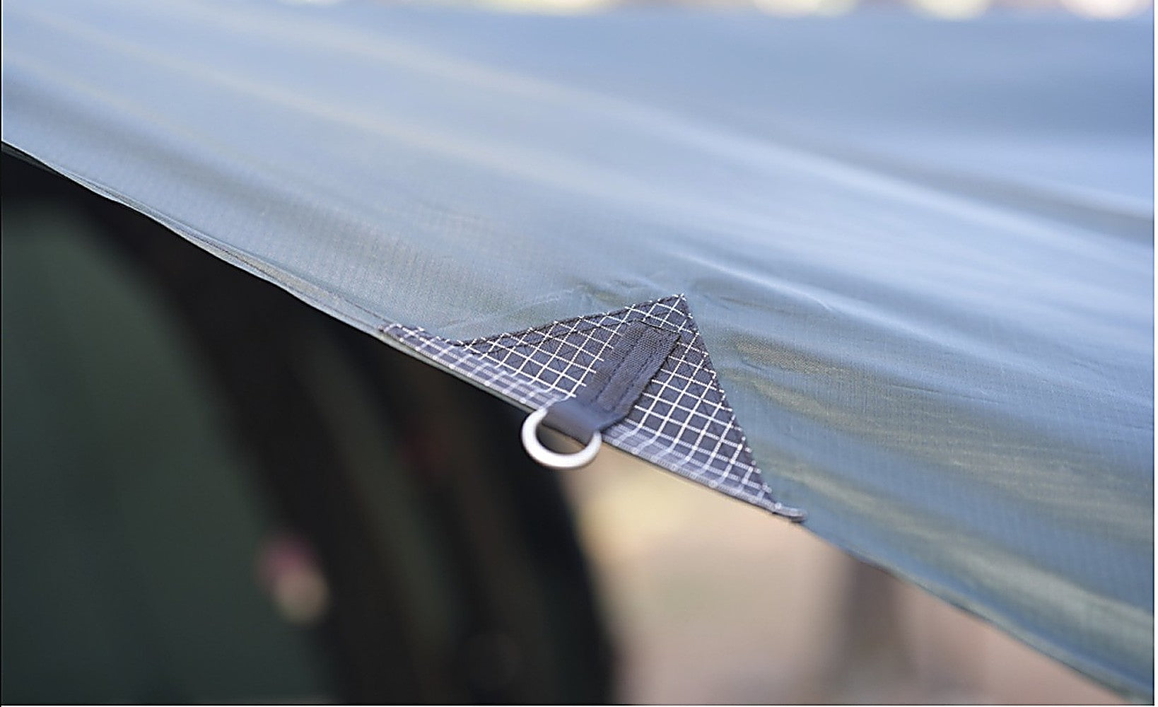 Detail of T720+ Side Tarp edge with reinforced grid corner and guy-line ring on the black-coated fabric
