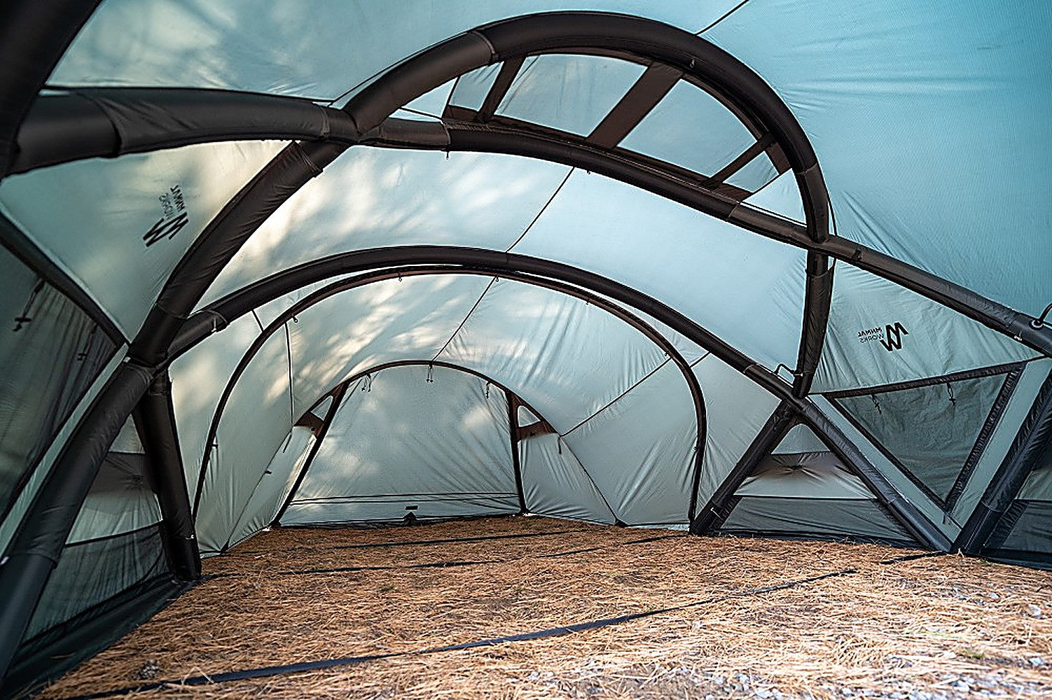 Interior of Minimal Works Shelter GM Vestibule showing arched frame poles over an open pine-needle floor