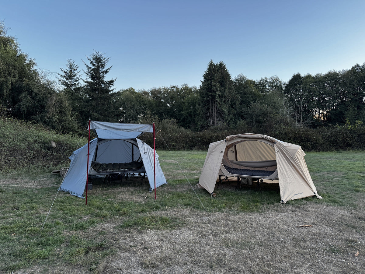 Natural and Air cot tents side by side under their rainflies, the Air with door poles (tents, cots, poles sold separately).