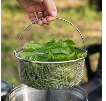 Hand lifting the mesh strainer filled with fresh lettuce out of the pot
