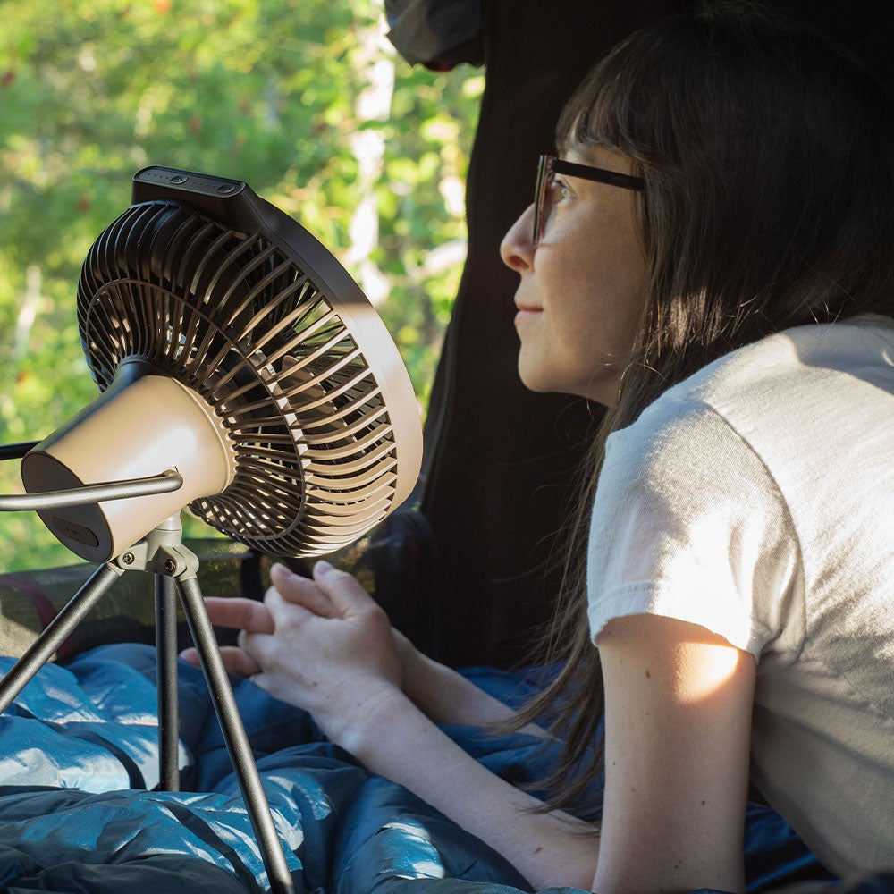 Camper lying in a tent with the V600+ fan running on its tripod