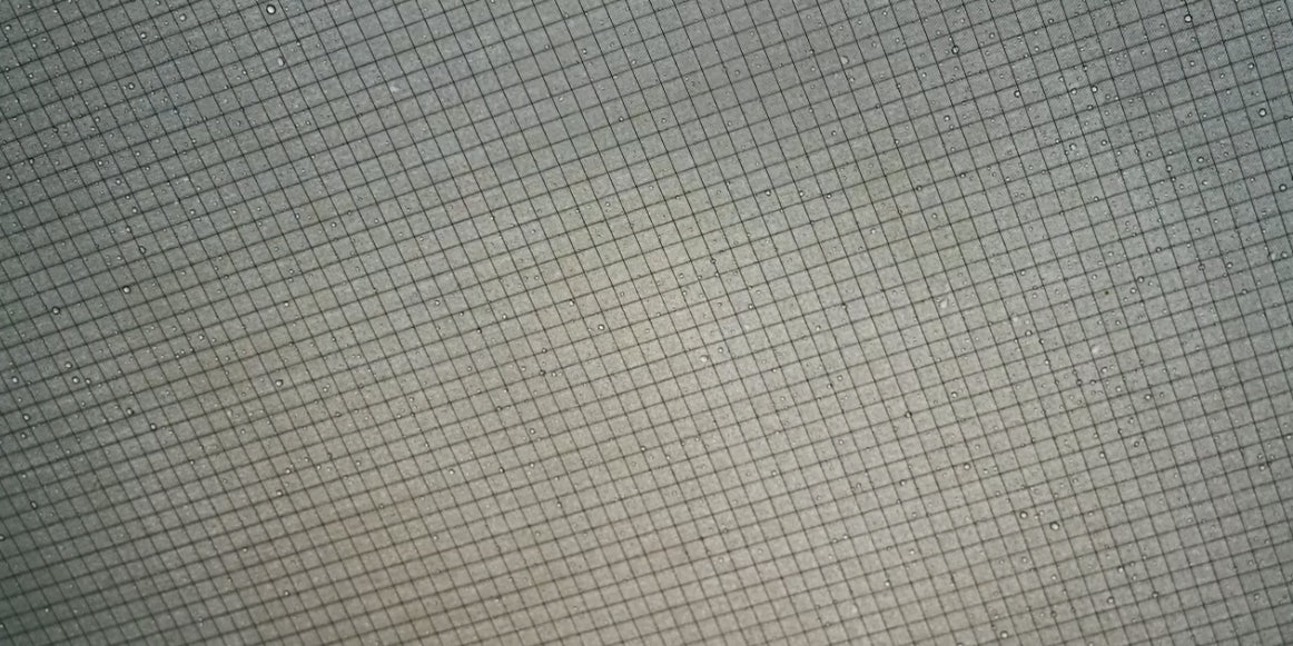 Black honey-comb weave fabric next to grey ripstop fabric showing texture difference