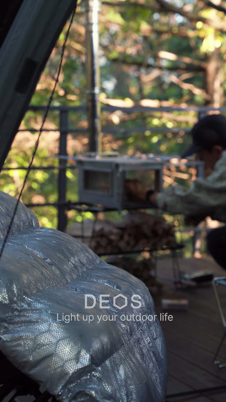 DEOS comforter at a campsite at dusk, stove glowing