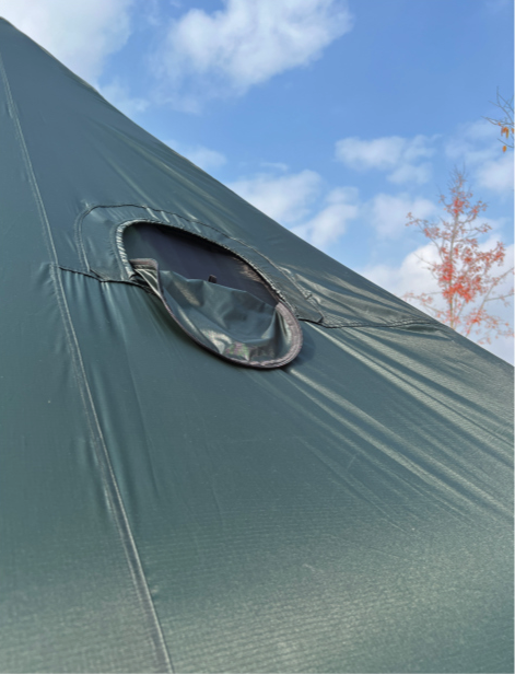 Gopamir G450 Air Shelter oval mesh-backed vent port on Dark Green canopy with blue sky and tree visible behind