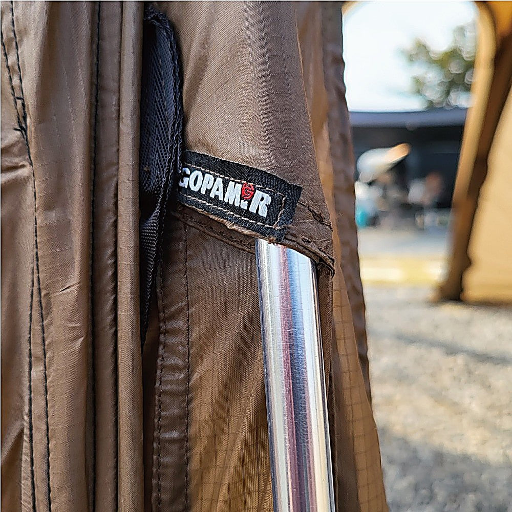 T720+ spare pole seated in a brown ripstop sleeve below the woven Gopamir label, campsite blurred behind