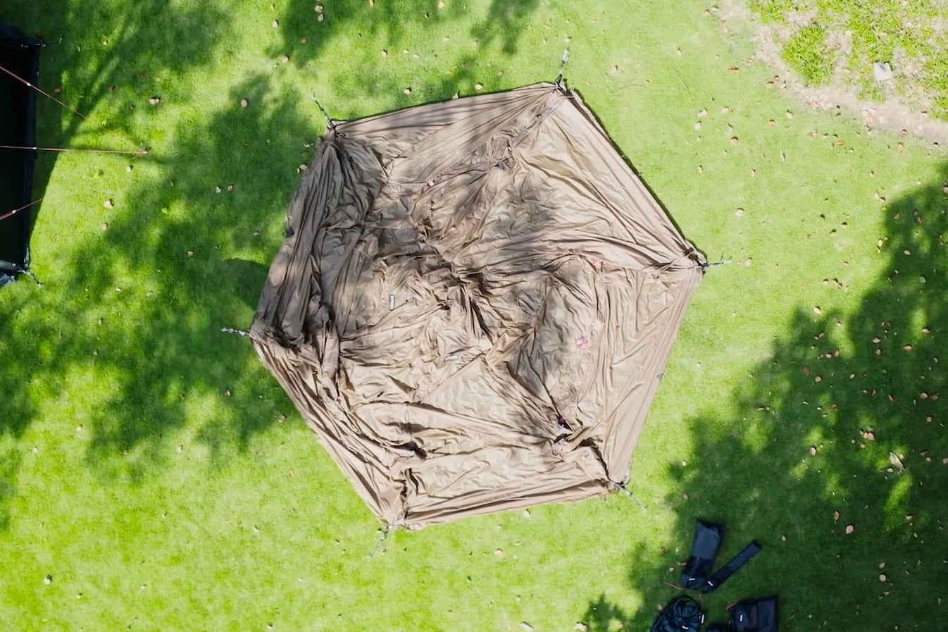 Gopamir G450 tent pitched on grass with user carrying packsack walking toward it