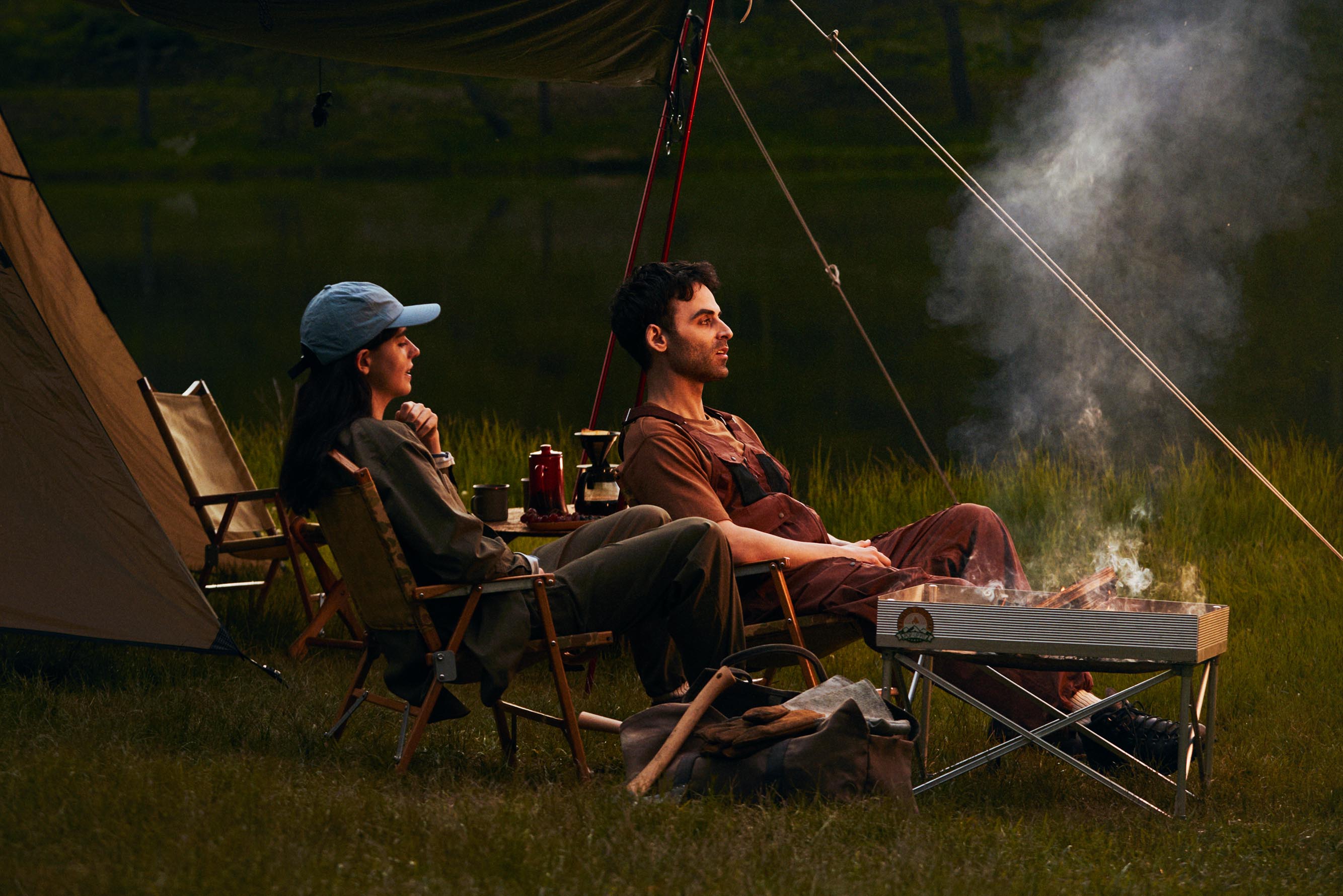 Two person sitting on the chairs on a campground