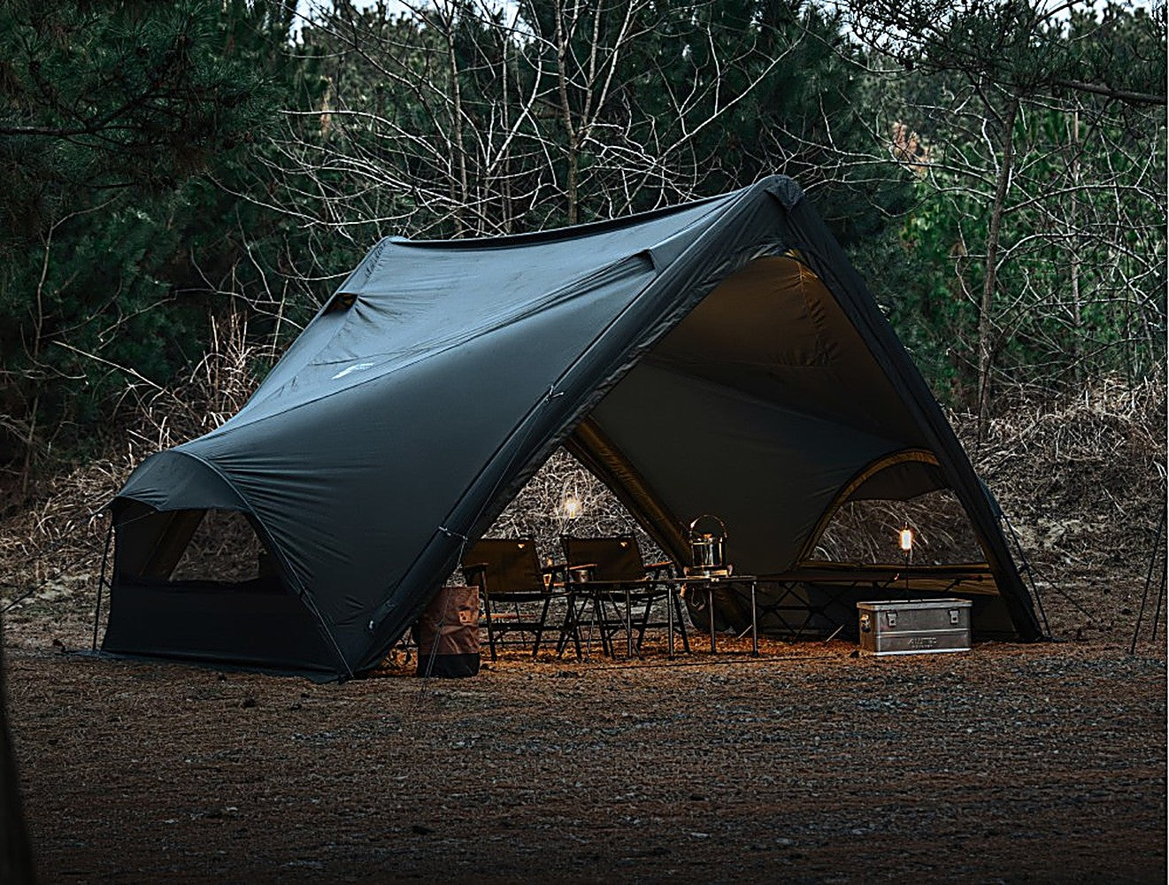 MGX-600 shelter with TPU door at dusk, warm-lit interior with chairs and table conveying a cozy cabin