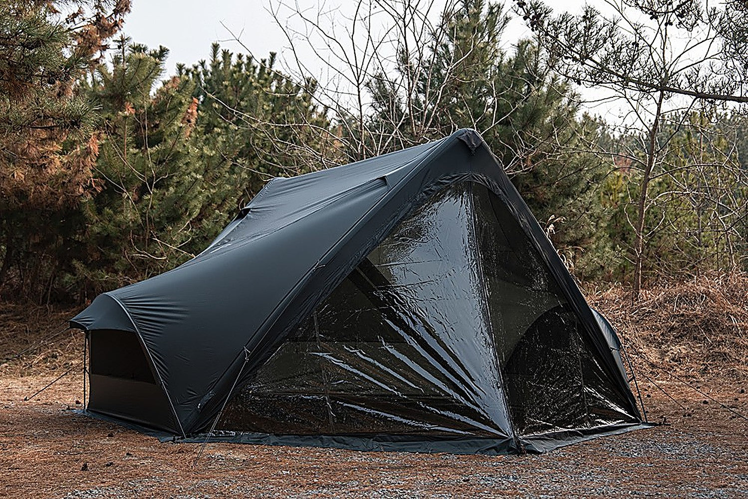 Three-quarter view of the MGX-600 shelter with the clear TPU front door fitted in a pine forest