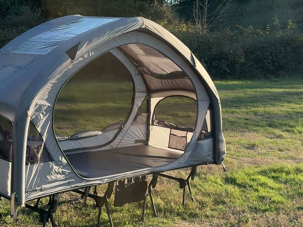 Neo Nest 80 Air in a field with its included roof cover fitted, on a camp cot (cot sold separately).