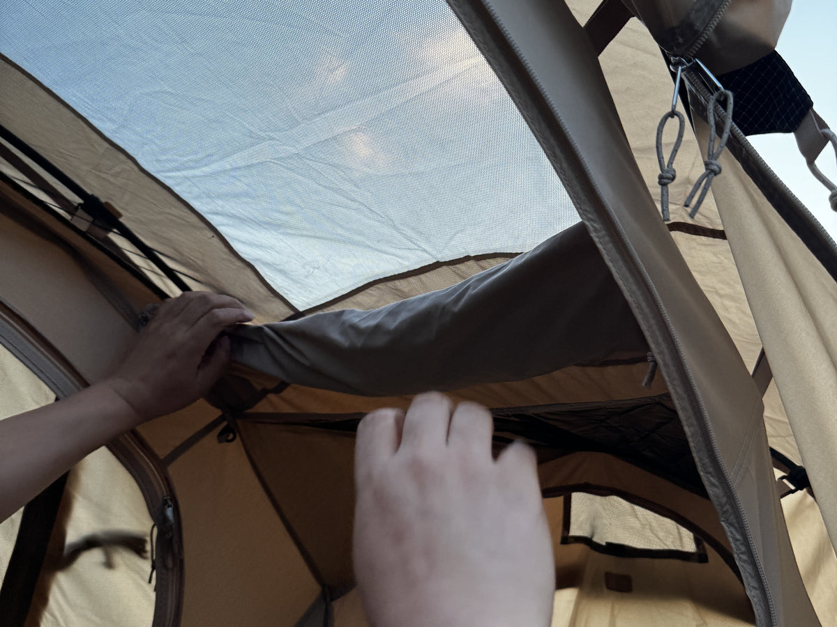 Hands unzipping the ceiling window panel of the Neo Nest 80 to open the mesh roof.