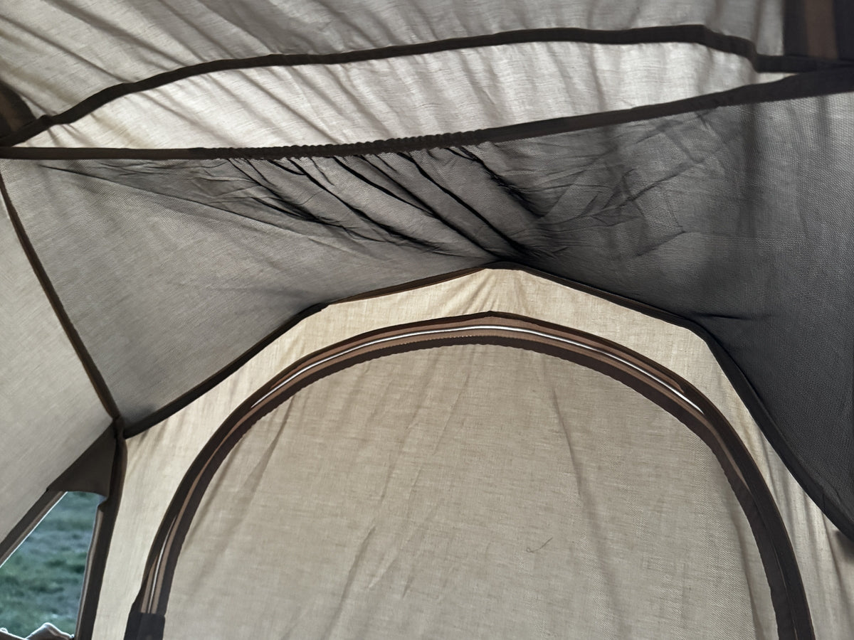 Soft daylight through the poly-cotton ceiling of the Neo Nest 80, with the mesh storage loft above the end door.