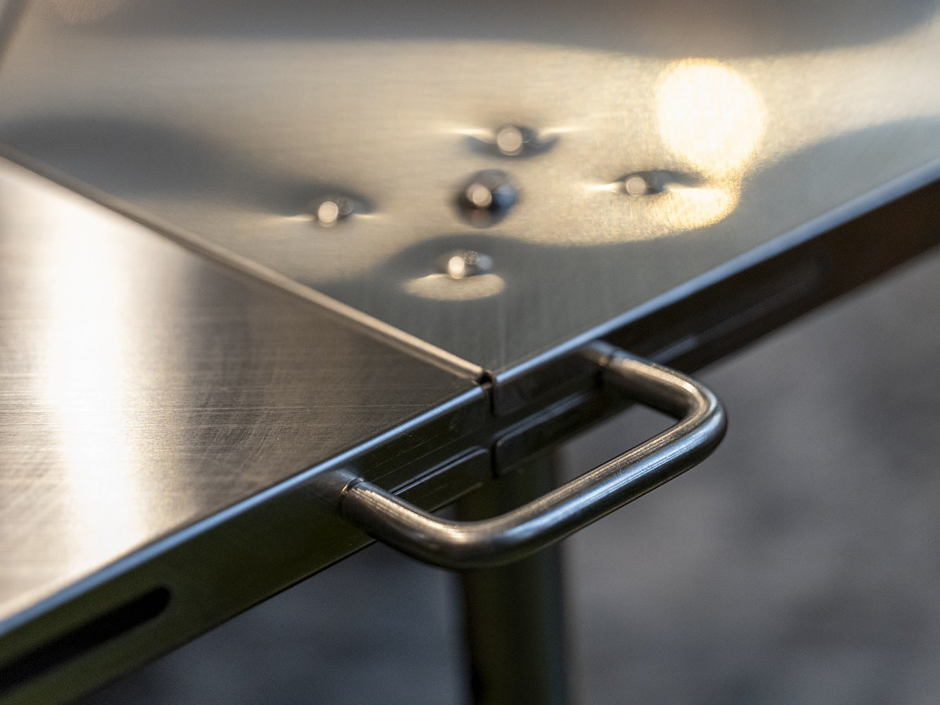 Close-up of an Octa table corner: stainless handrail, deburred plate edge, connect-hole rivets and the IGT rail slot alongside.
