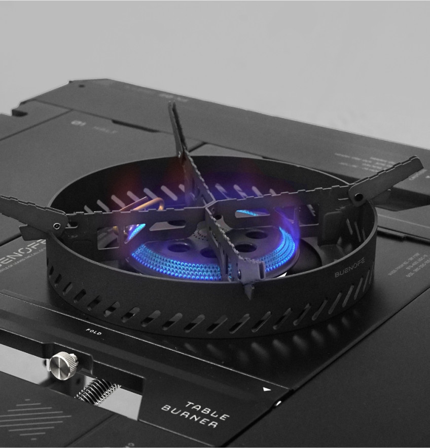 BUENOFE Stove Windscreen surrounding the lit BX-09 Table Burner, its ring glowing against a dark background as a steady blue and violet flame burns inside, illustrating how the shield keeps firepower stable in wind.