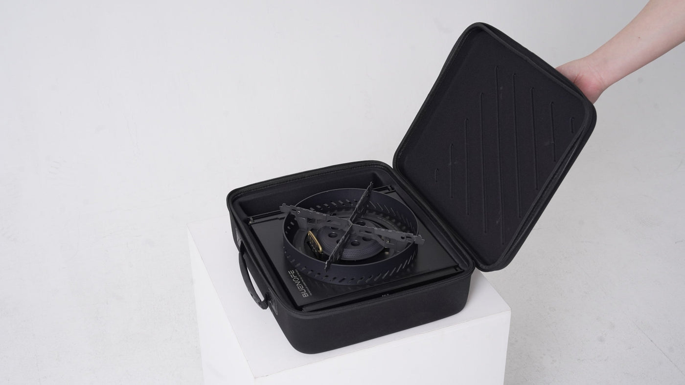 BUENOFE Stove Windscreen and BX-09 Table Burner nested inside an open black EVA hard carry case held by a hand, showing how the ring and burner pack together for transport and storage.
