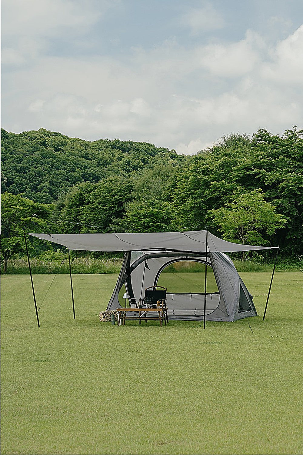 GEO AIR4 Extension Sun Shade pitched over a gray air tent on a grass campsite, camp table and chair beneath the canopy