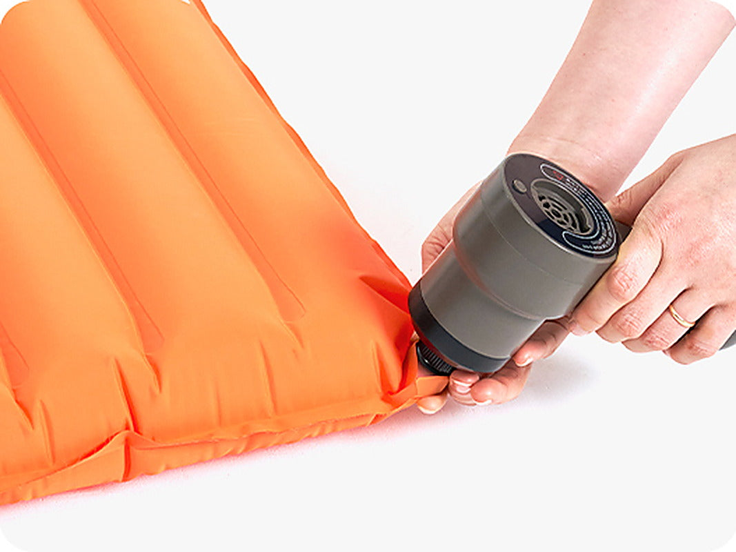 Tornado 25 air pump held against the valve of an orange air mat while inflating it (mat sold separately).